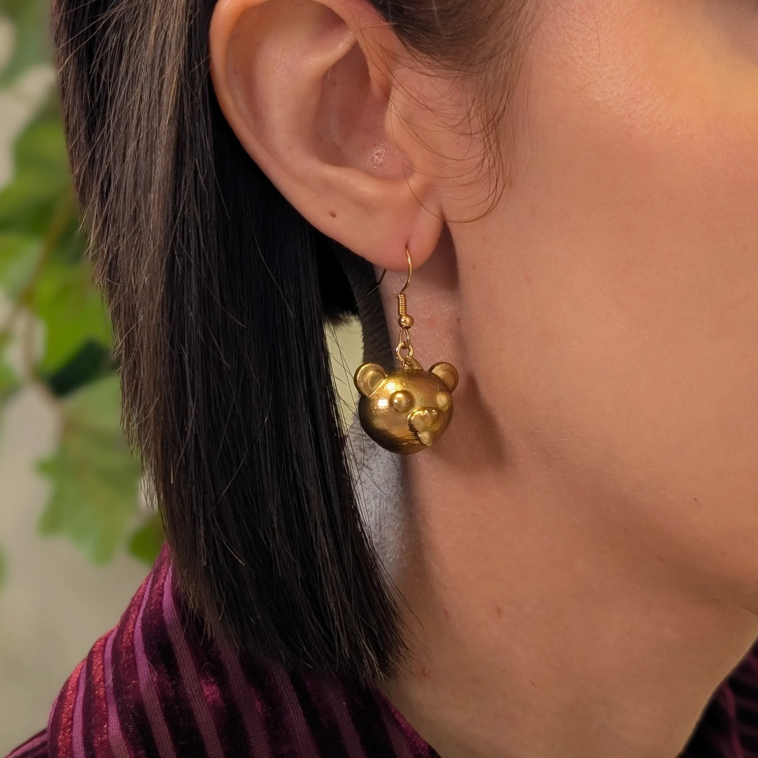 Cuddle head gold earrings worn on a model