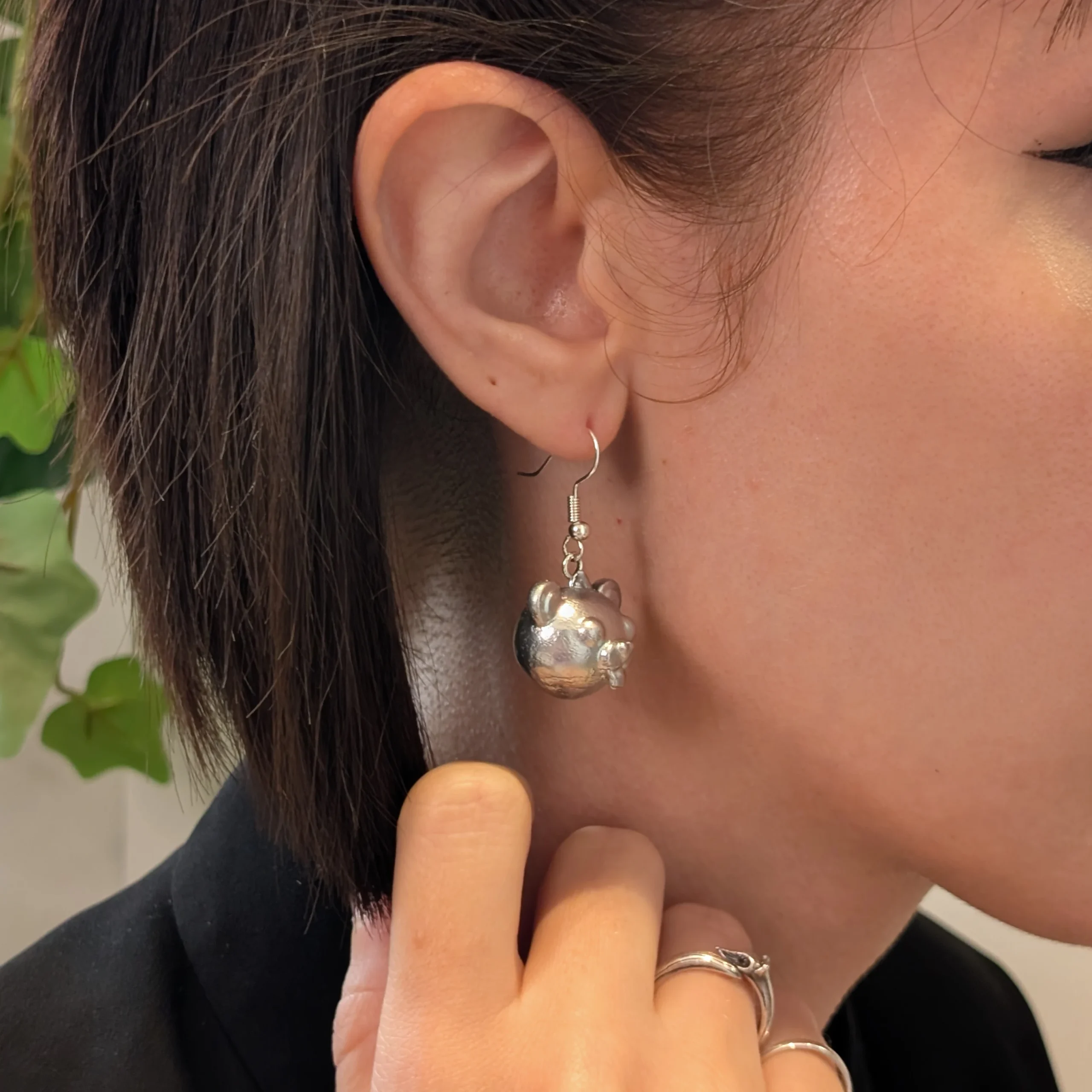 Cuddle head silver earrings worn on a model